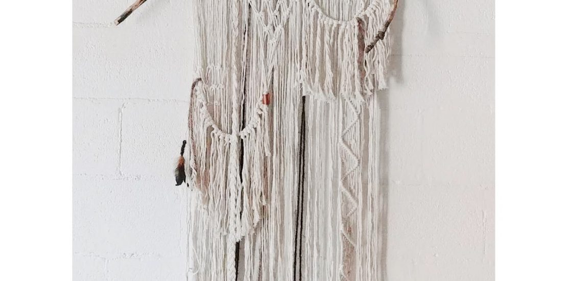 Horizontal stick with macrame and feathers hanging on a wall