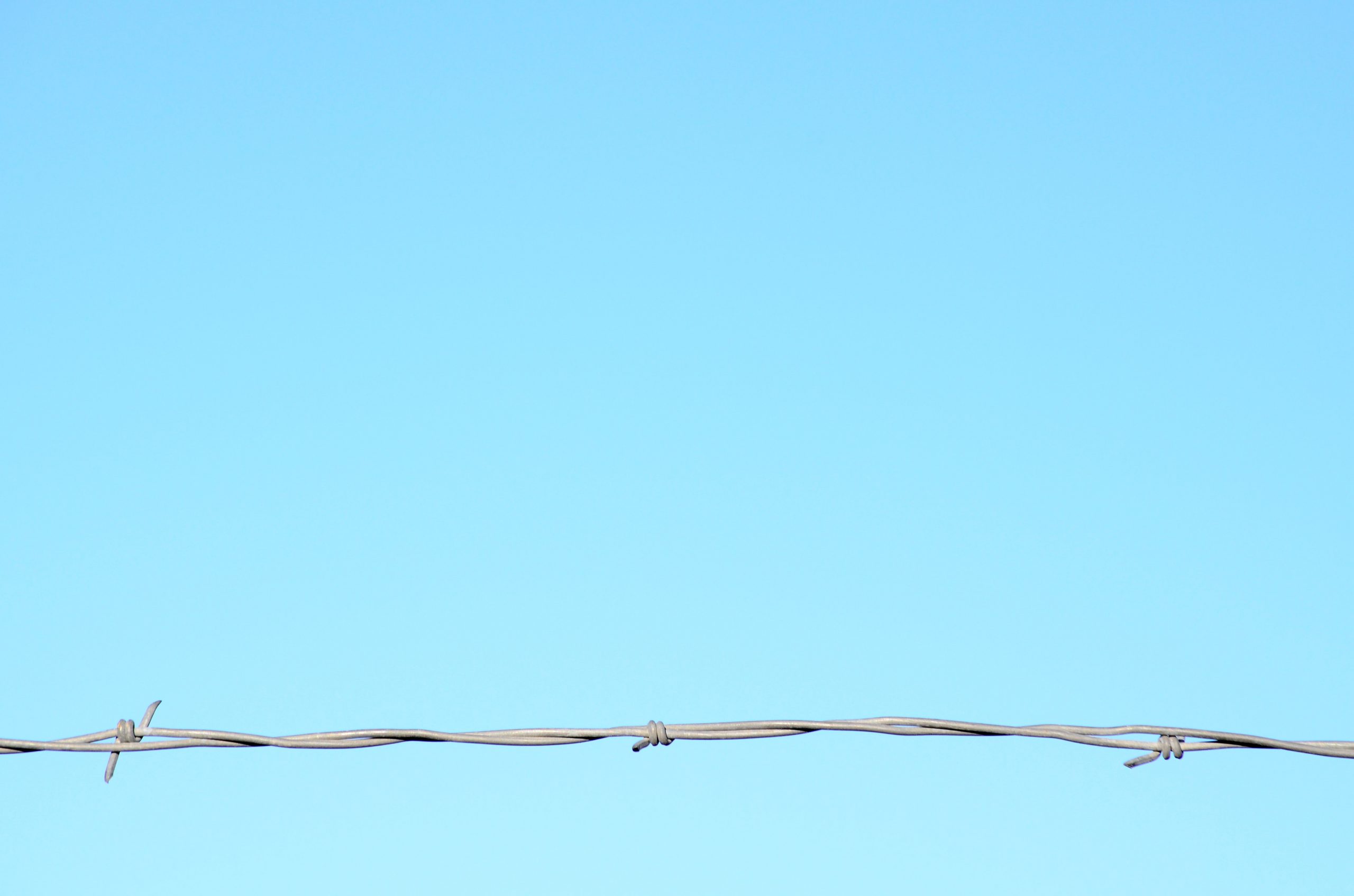 Close-up of razor wire against a clear blue sky